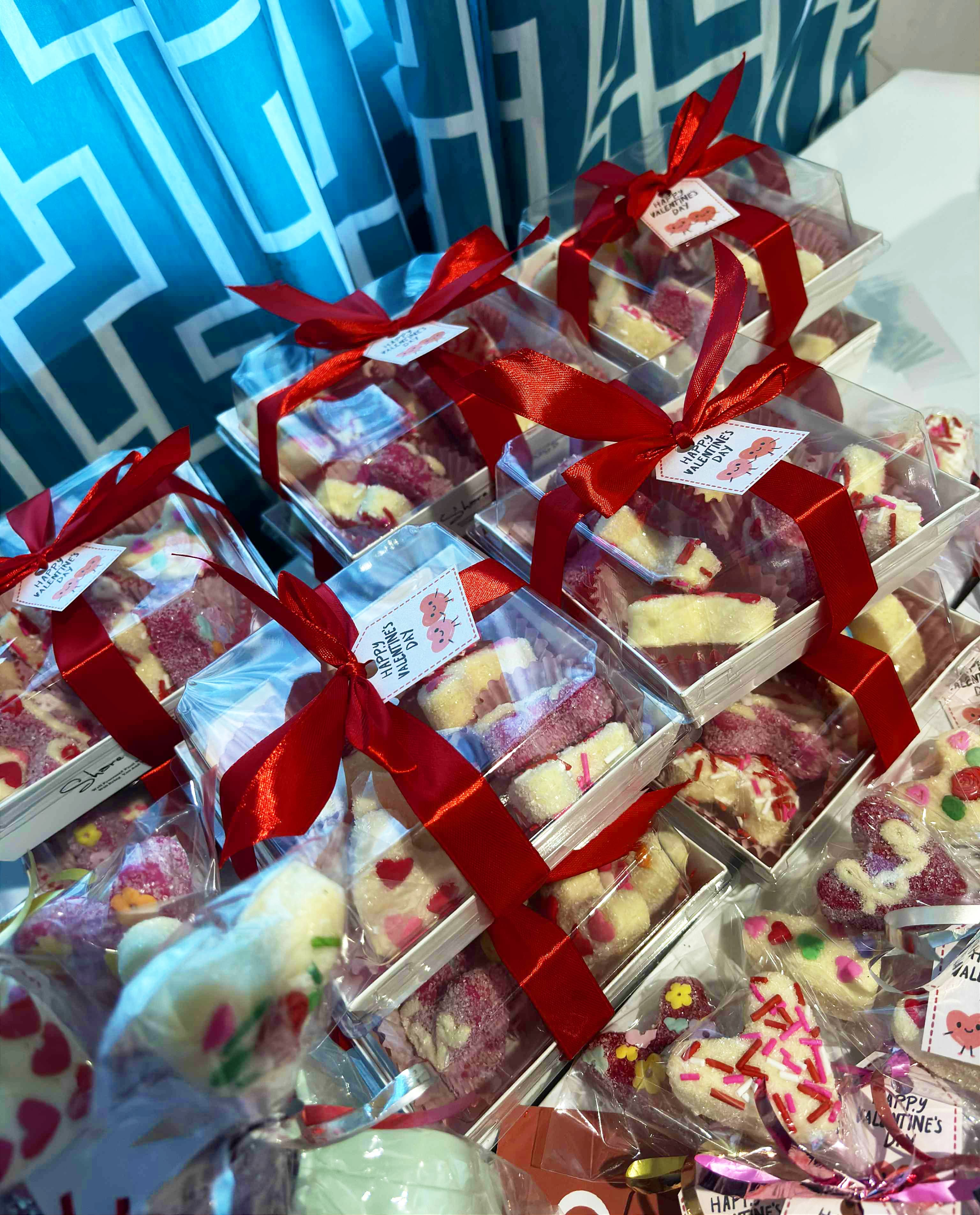 Heart-shaped cookies in clear gift boxes tied with red ribbons and Happy Valentine's Day tags.