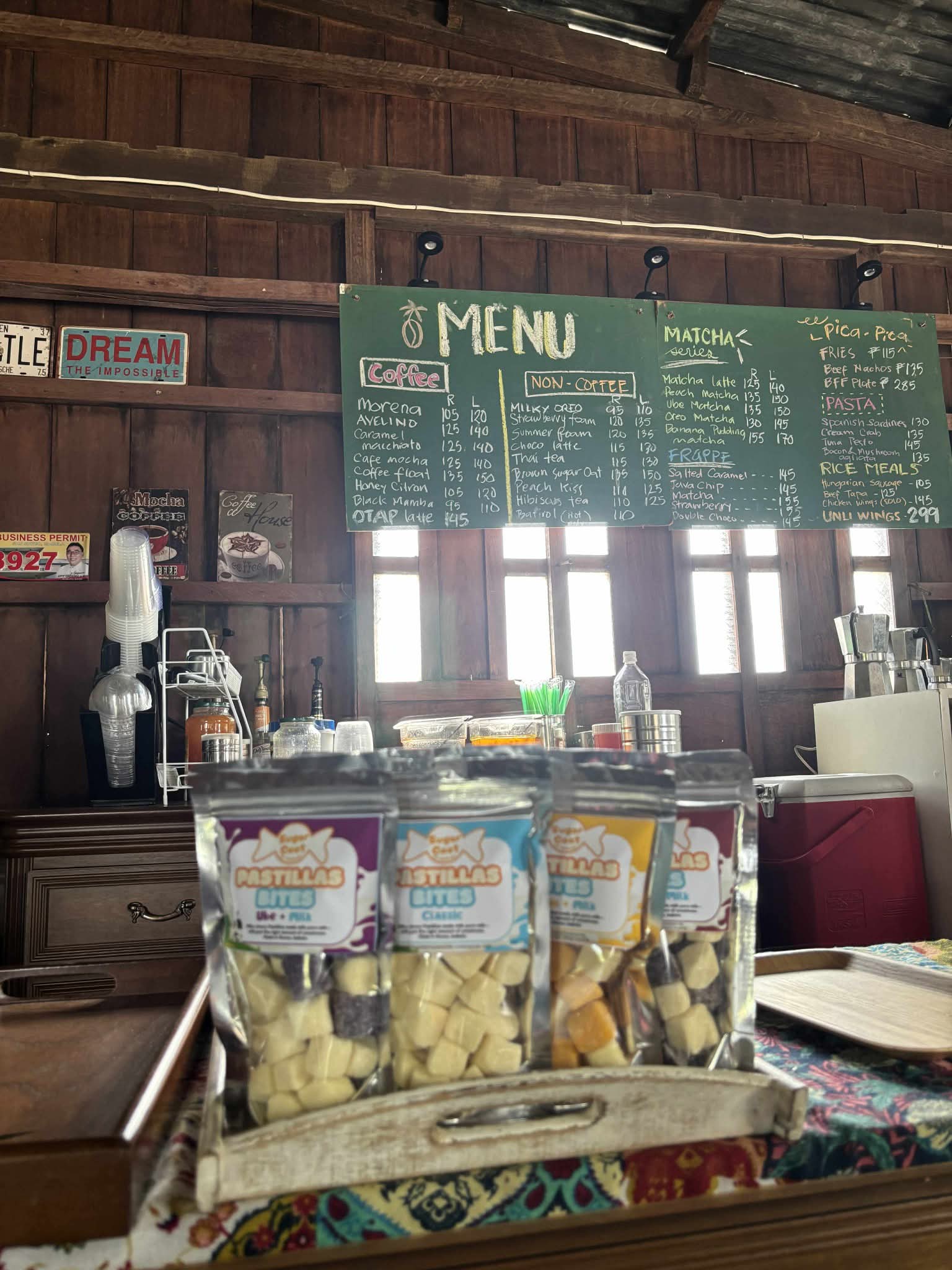 Pastillas Bites snacks on a tray in a rustic cafe with a handwritten chalkboard menu.